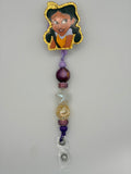 Penny Proud-inspired badge reel with gold-glitter character outline, purple and lavender beads, pink sparkling spacers and a clear snap strap.