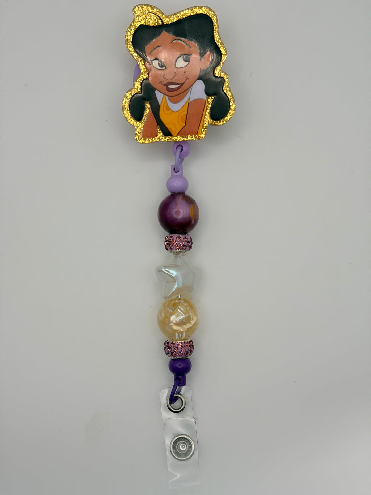 Penny Proud-inspired badge reel with gold-glitter character outline, purple and lavender beads, pink sparkling spacers and a clear snap strap.