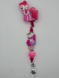 Pink pony-themed badge reel with a sparkly border, pony-and-cupcake charm, pink beads, and clear snap badge strap.