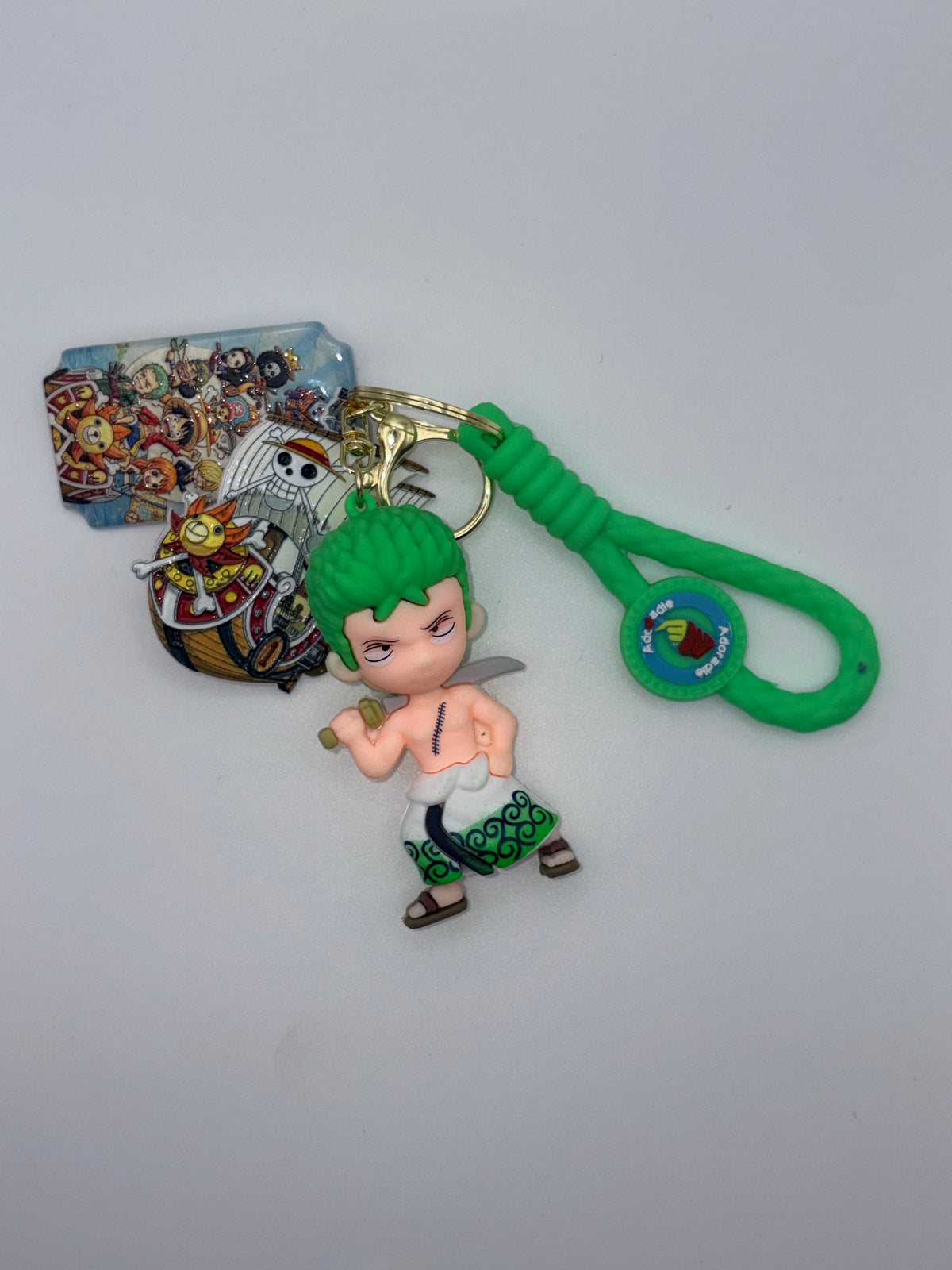 Zoro-themed keychain with green-haired swordsman charm, bright green loop, pirate ship charm, character-collage charm, and gold-tone key ring.
