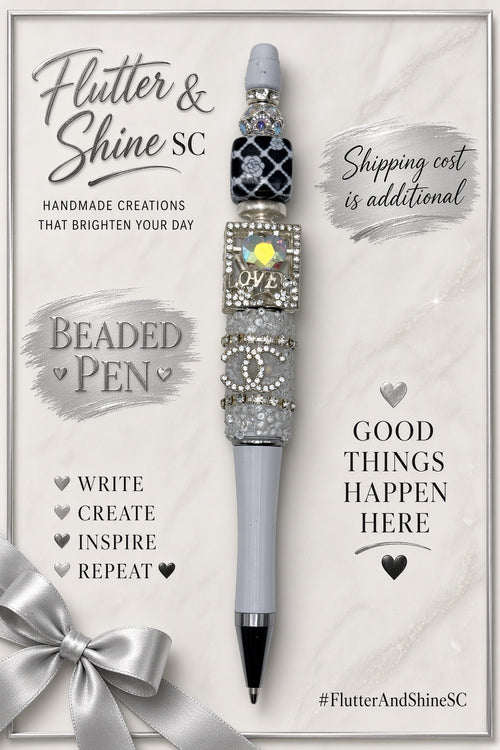 Gray and silver-tone LOVE beaded pen displayed on a Flutter & Shine SC branded background with a decorative silver bow; display props are not included.