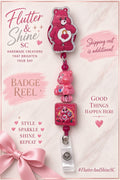 Pink Care Bears themed badge reel with heart-lock belly emblem, sparkling silver-tone border, pink bear-shaped bead, square bear illustration accent, and clear snap badge strap.