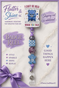 Grumpy Bear themed badge reel with blue bear statement topper, purple beads, blue-and-white checkerboard bead, faceted sparkle accents, blue bear detail, and clear snap badge strap.