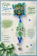 Teenage Mutant Ninja Turtles Themed badge reel with four-turtle topper, light-blue glitter border, pale-green character accent, green and purple beads, blue accents, and clear snap badge strap.